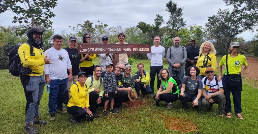 Voluntários do CPC reunidos junto à placa Construímos trilhas para preservar